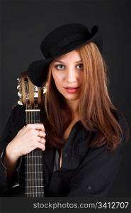 Portrait of a young attractive woman with a guitar on a black background