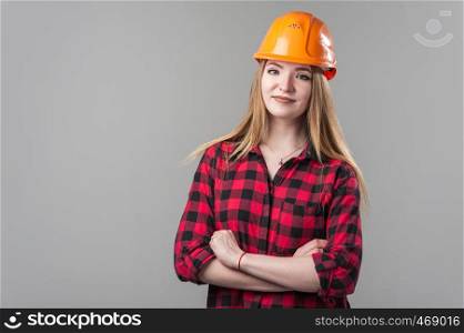 Portrait of a young attractive woman with blond hair in orange helmet and in a plaid shirt on a neutral gray background.. Portrait of a young attractive woman with blond hair in orange helmet on a neutral gray background.