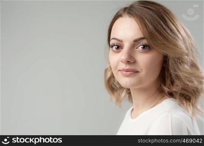 Portrait of a young attractive woman with blond hair on a neutral gray background. Close up.. Portrait of a young attractive woman with blond hair on a neutral gray background.