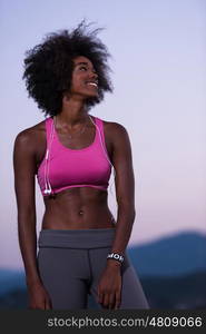 portrait of a young beautiful african american woman with headphones jogging in nature beautiful summer night