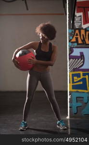 portrait of a young beautiful African American women carrying crossfit ball in gym