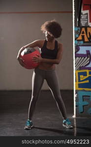 portrait of a young beautiful African American women carrying crossfit ball in gym