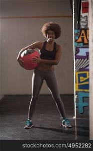portrait of a young beautiful African American women carrying crossfit ball in gym