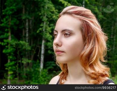 portrait of a young beautiful blonde girl in the park on summer day closeup