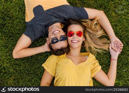 Portrait of a young beautiful couple lying on the grass