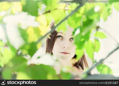 Portrait of a young beautiful girl in the foliage closeup