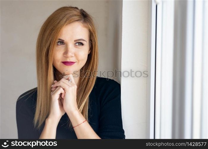 Portrait of a young beautiful girl near a window with natural lighting