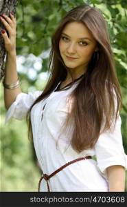 Portrait of a young beautiful girl standing near birch