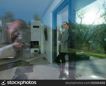 portrait of a young beautiful successful woman drinking coffee in the doorway of her luxury home villa