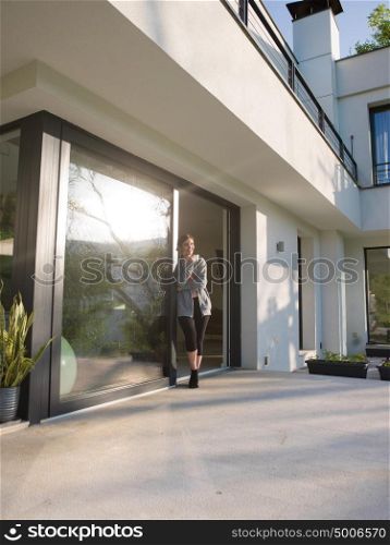 portrait of a young beautiful successful woman drinking coffee in the doorway of her luxury home villa