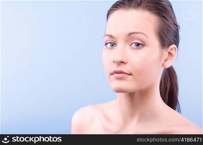 portrait of a young beautiful woman looking at camera, on blue background