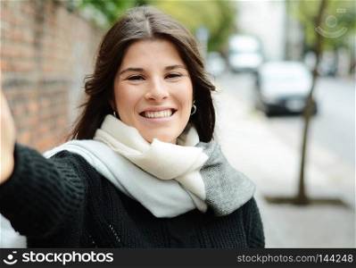 Portrait of a young beautiful woman taking selfie. Outdoors.