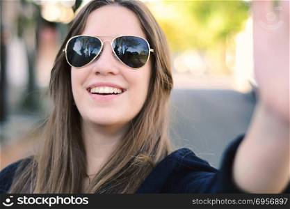 Portrait of a young beautiful woman taking selfie. Outdoors.. Portrait of young woman taking selfie.