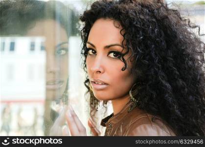 Portrait of a young black woman, afro hairstyle, wearing beige leather jacket, in urban background