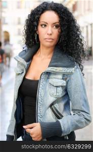 Portrait of a young black woman, afro hairstyle, wearing dening jacket in urban background