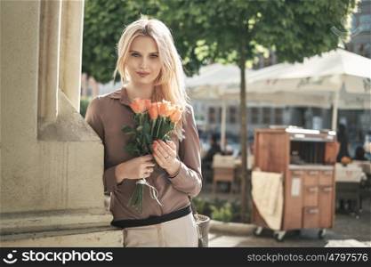 Portrait of a young blond woman with a bunch of fresh roses