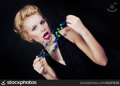 Portrait of a young blonde woman with beads on black background