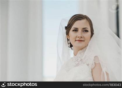 Portrait of a young bride about the white columns.. Portrait of a girl in a white dress and veil around the columns 4025.