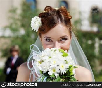 Portrait of a young bride in a white dress with a bouquet of flowers.