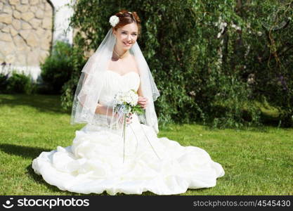 Portrait of a young bride in a white dress with a bouquet of flowers.