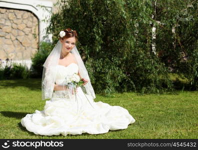 Portrait of a young bride in a white dress with a bouquet of flowers.