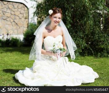 Portrait of a young bride in a white dress with a bouquet of flowers.