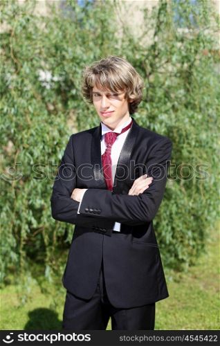 Portrait of a young bride in nature in a dark suit and red tie