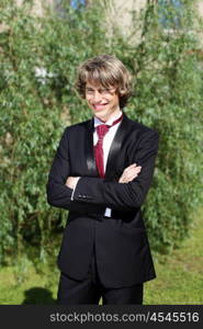 Portrait of a young bride in nature in a dark suit and red tie