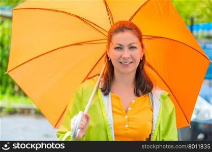 Portrait of a young brunette with an orange umbrella closeup