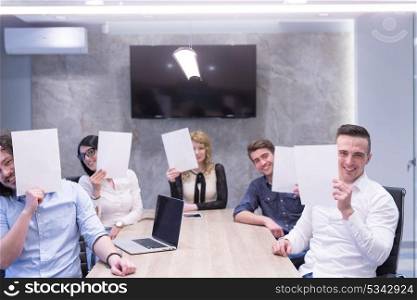 Portrait of a young business team holding a white paper over their face in the startup office