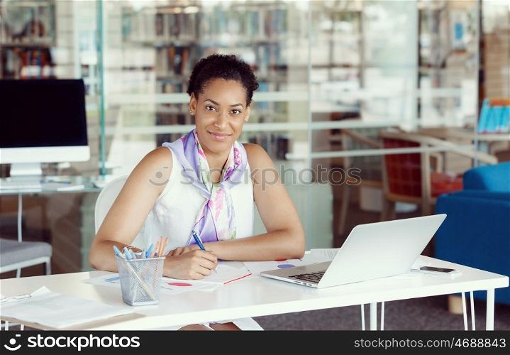 Portrait of a young business woman working on a laptop in a office