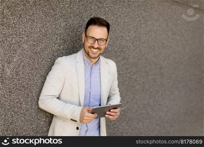 Portrait of a young businessman holding digital tablet outdoor in urban enviroment
