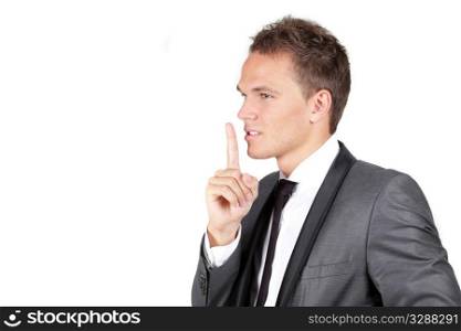 Portrait of a young businessman showing silence gesture with his forefinger isolated