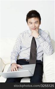 Portrait of a young businessman sitting with a laptop