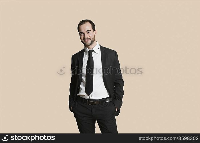 Portrait of a young businessman with hands in pockets over colored background