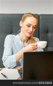 Portrait of a young businesswoman using laptop sitting at the table with a cup of coffee in a cafe. Portrait of a young businesswoman
