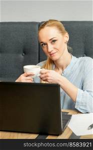 Portrait of a young businesswoman using laptop sitting at the table with a cup of coffee in a cafe. Portrait of a young businesswoman