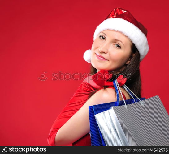 Portrait of a young charming girl dressed as Santa with a bag of shopping in their hands. Happy New Year!