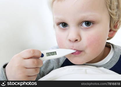 Portrait of a young child with a thermometer in his mouth measuring his fever