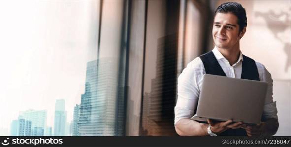 Portrait of a Young Confident CEO or Leader Working on Computer Laptop in the Modern Workplace. Smiling Businessman Standing by the Window and Looking outside
