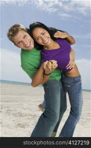Portrait of a young couple dancing on the beach and smiling