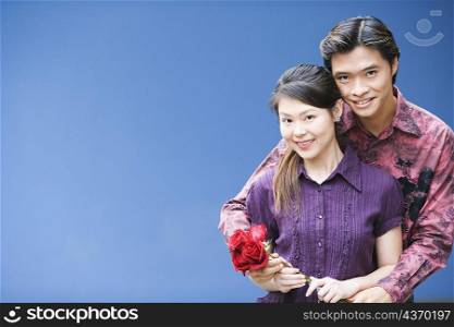 Portrait of a young couple holding a bunch of roses and smiling