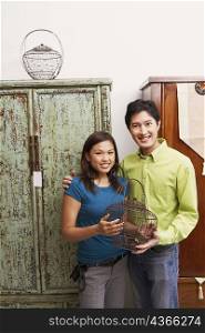 Portrait of a young couple holding a cage and smiling