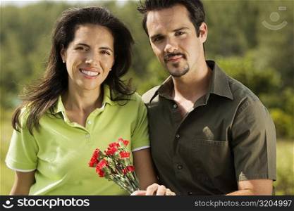 Portrait of a young couple holding flowers