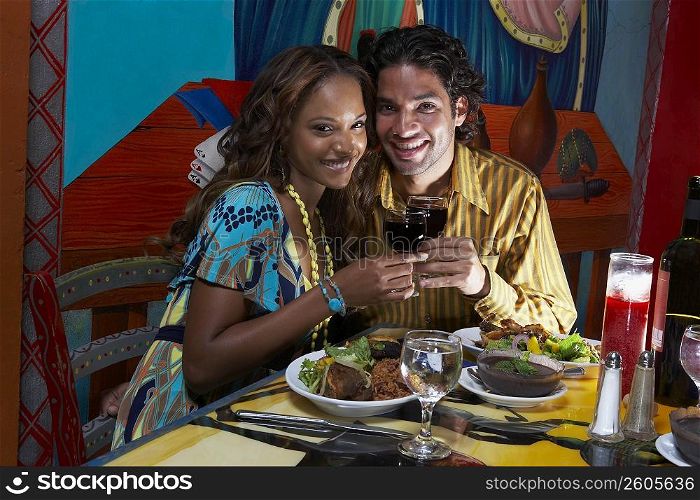 Portrait of a young couple holding wine glasses and smiling in a restaurant
