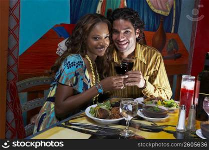 Portrait of a young couple holding wine glasses and smiling in a restaurant