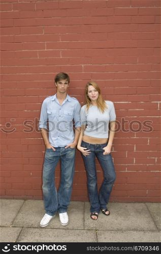 Portrait of a young couple leaning against a wall