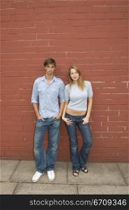 Portrait of a young couple leaning against a wall