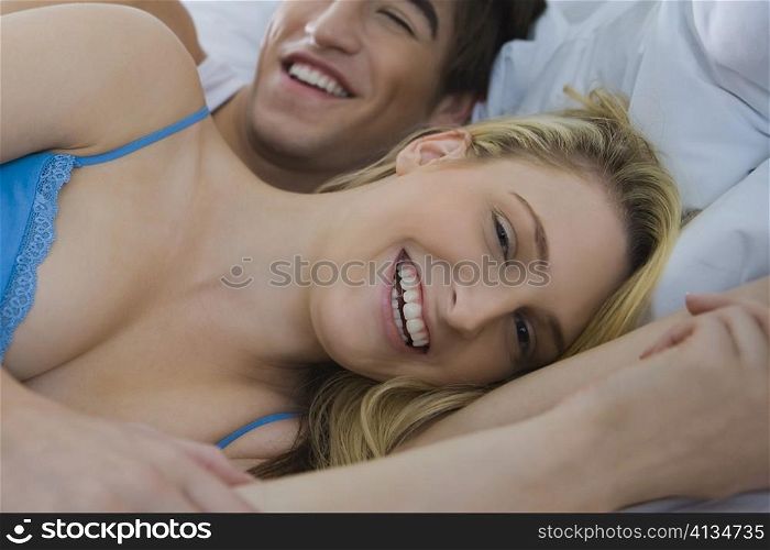 Portrait of a young couple lying on the bed and smiling