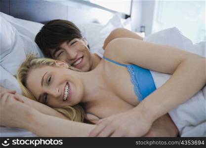 Portrait of a young couple lying on the bed and smiling